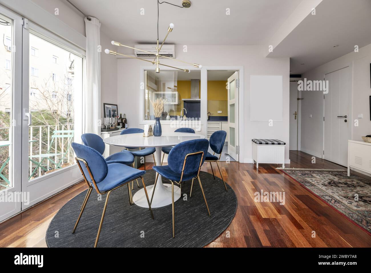 A circular white wooden dining table next to a kitchen with serving hatch window Stock Photo Alamy