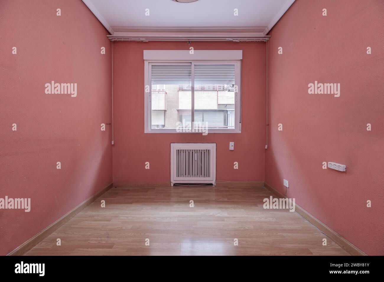 An empty room with terracotta painted walls, plaster moldings on the ...