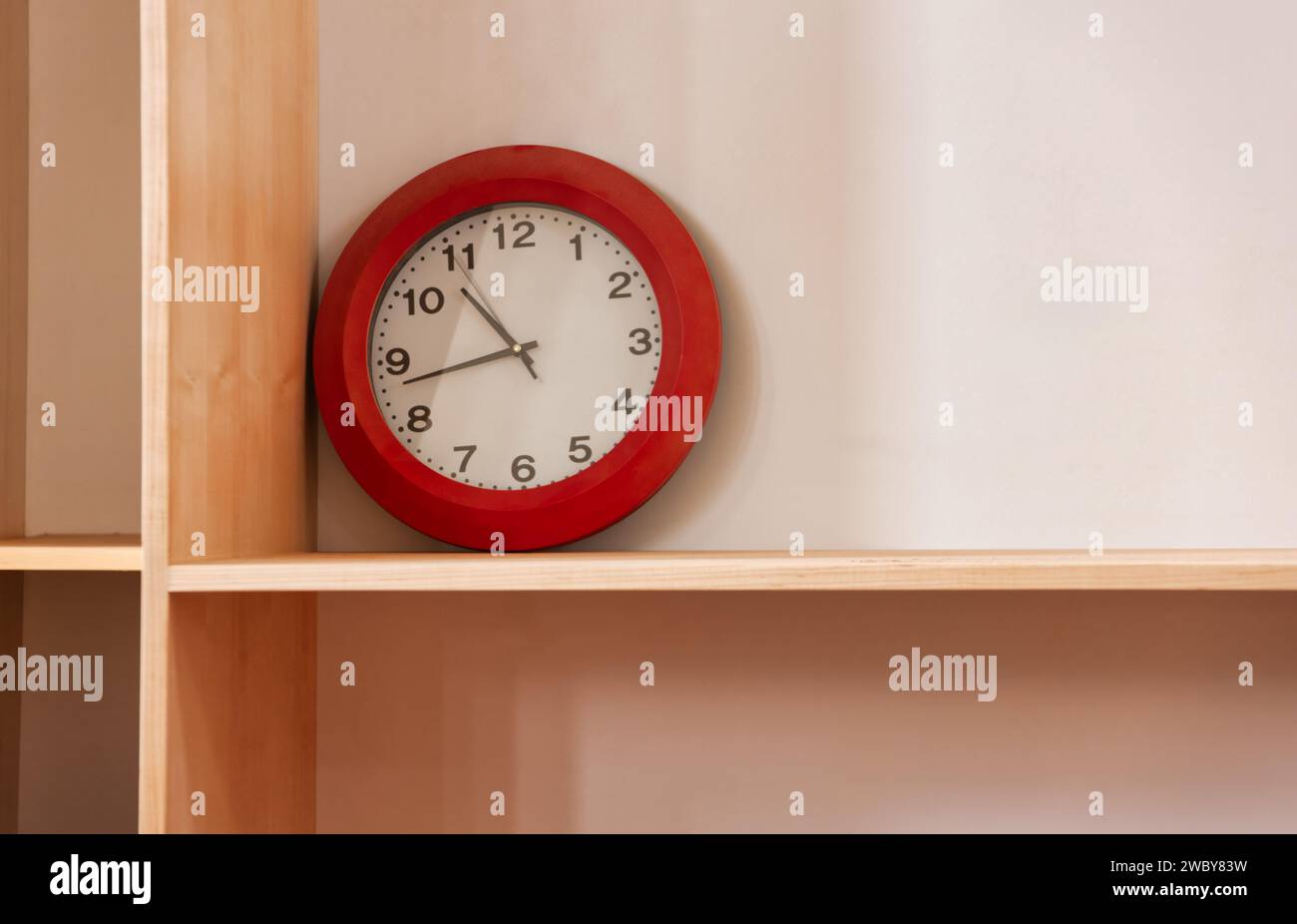 wall clock with red frame on wooden shelves Stock Photo Alamy