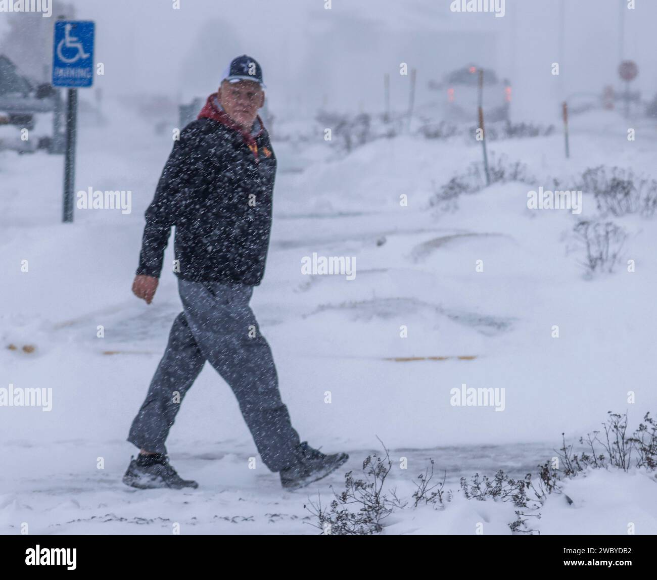 Altoona, United States. 12th Jan, 2024. A man walks through a snowy parking lot as a winter