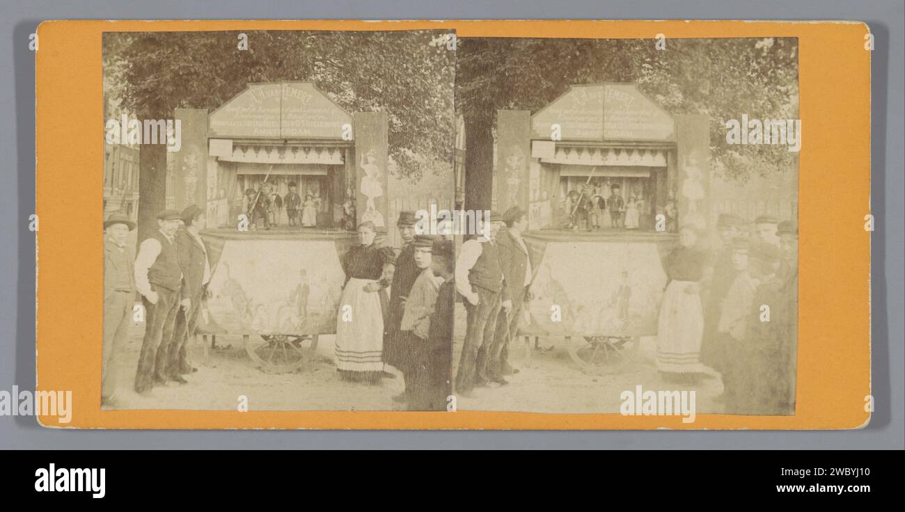Puppet cabinet from A.A. van Hemert, Amsterdam, Anonymous, c. 1886 - c. 1900 stereograph A group of people poses on either side of a puppet show. On the puppet show the text is: 'A.A. van Hemert plays with puppets or the Jan Klaassenkast at children's parties and school parties. Residence Suikerbakkerssteeg No 19 [...] Reguliersdwarsstraat Amsterdam'. Amsterdam cardboard. paper albumen print puppet and marionette show Amsterdam Stock Photo