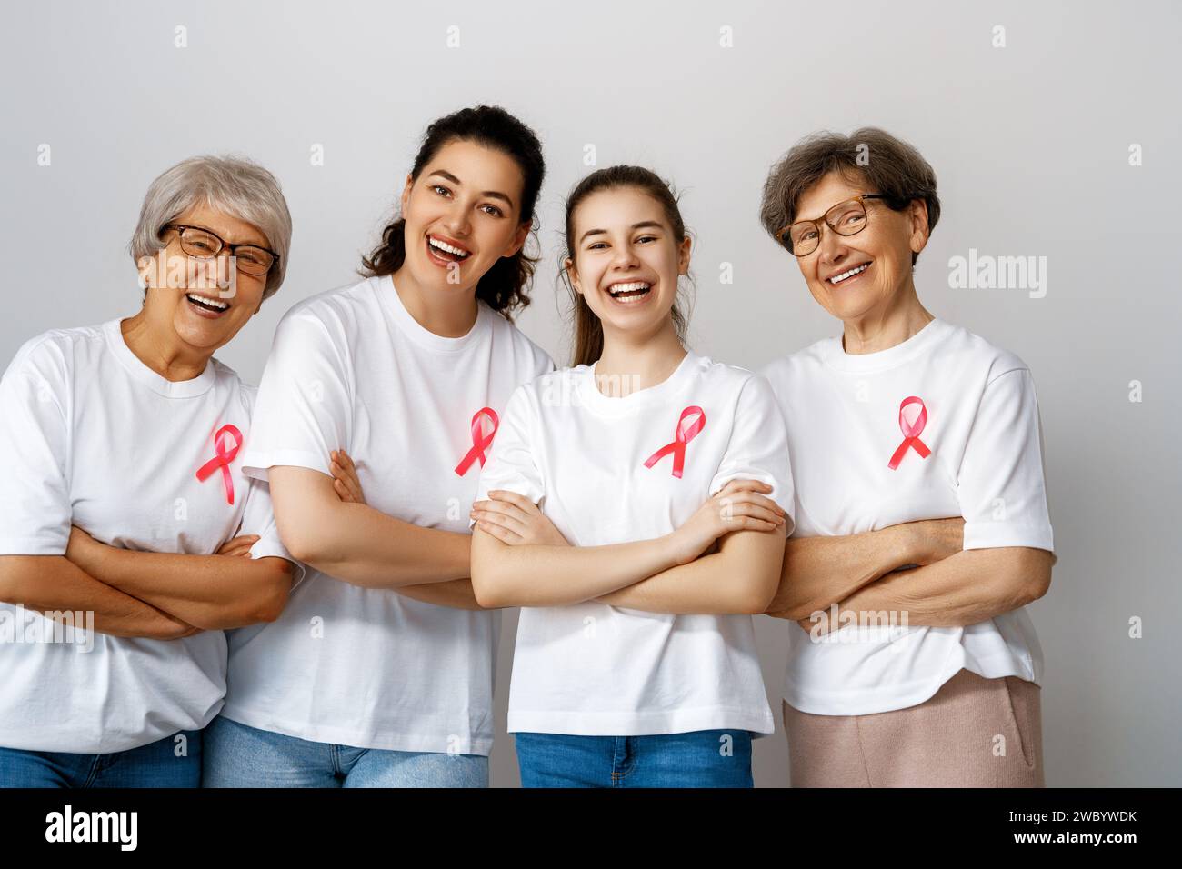 Smiling women with pink satin ribbon symbolizing concept of illness awareness, expressing solidarity and support for cancer patients and survivors. Di Stock Photo