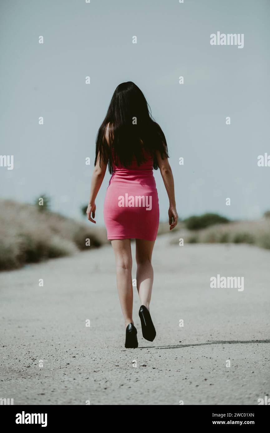 Woman in short pink dress walking away on urban road Stock Photo - Alamy