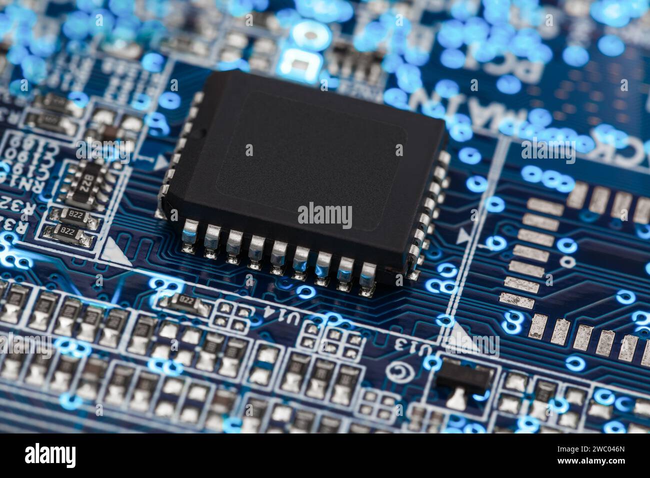 A microprocessor on a printed circuit board surrounded by auxiliary elements, backlit through the board. Macrofto in dark colors Stock Photo
