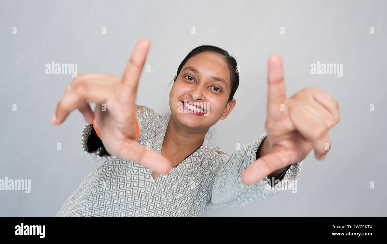 A happy young Indian girl inspired to capture an interesting shot frame gesture. Stock Photo