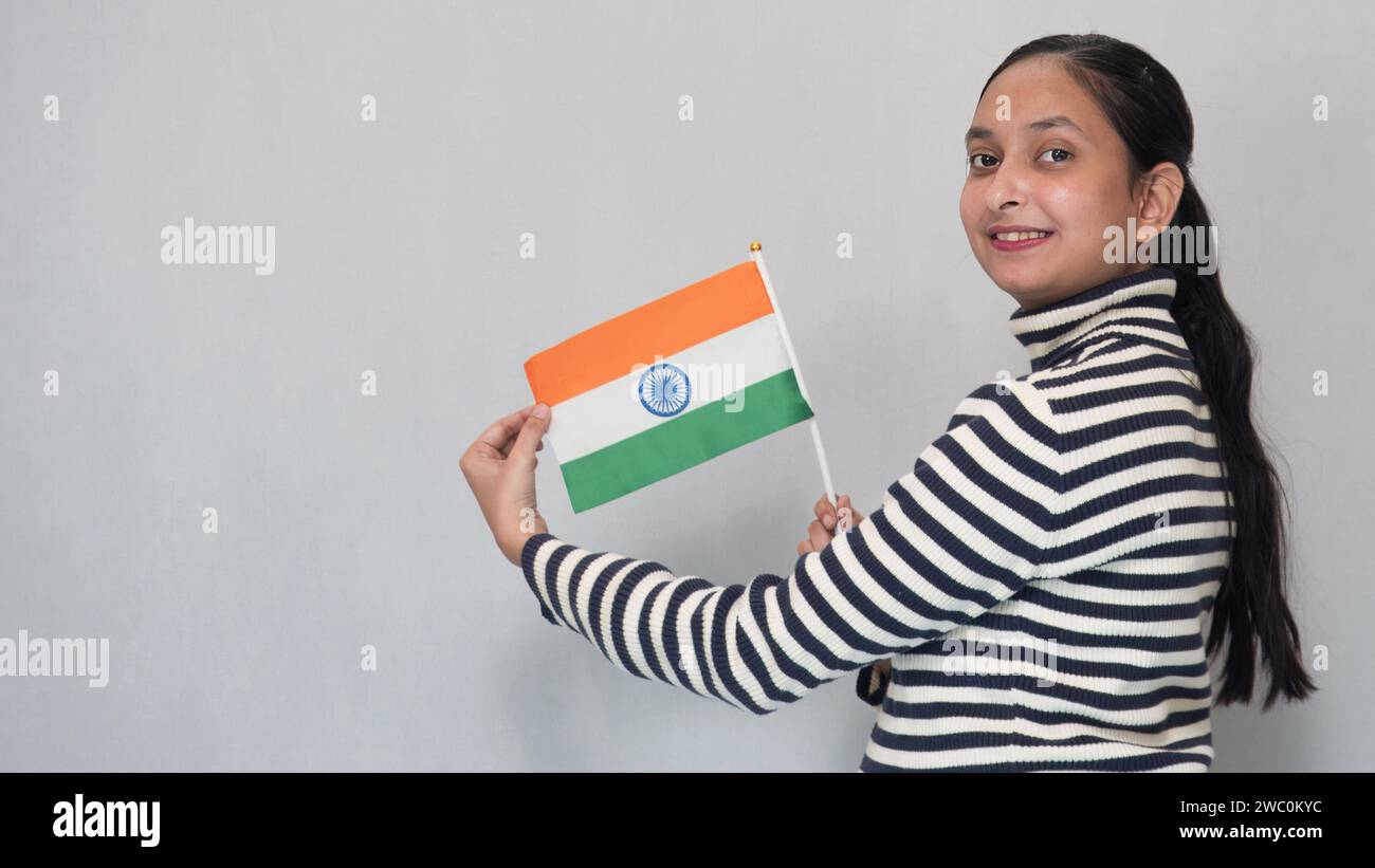 A young Indian girl wearing a striped sweater in winter with India tricolor flag Stock Photo