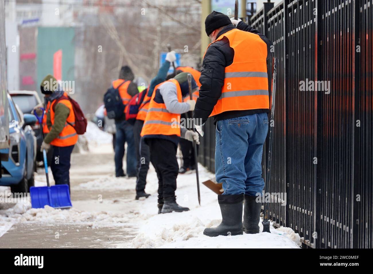 Workers with shovels and crowbars cleaning sidewalk, snow and melting ice removal in winter city