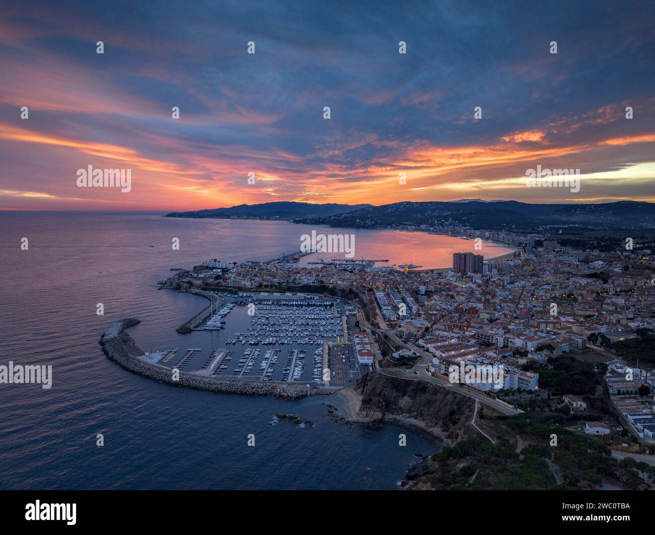 Sunset with a red sky over the bay and city of Palamós. Aerial view (Costa Brava, Baix Empordà, Girona, Catalonia, Spain) Stock Photo