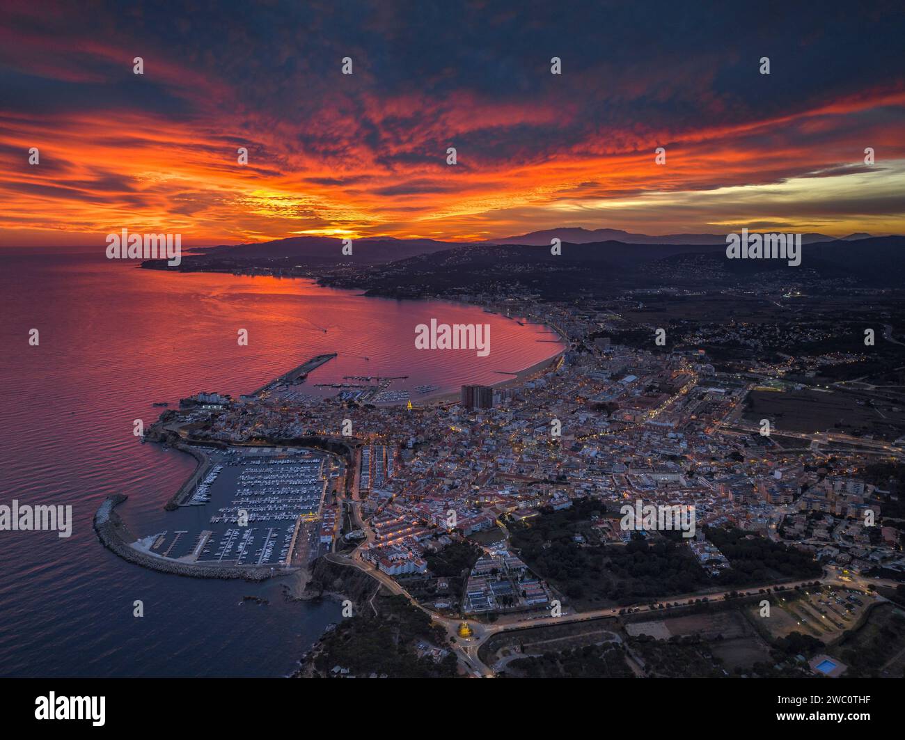 Sunset with a red sky over the bay and city of Palamós. Aerial view (Costa Brava, Baix Empordà, Girona, Catalonia, Spain) Stock Photo