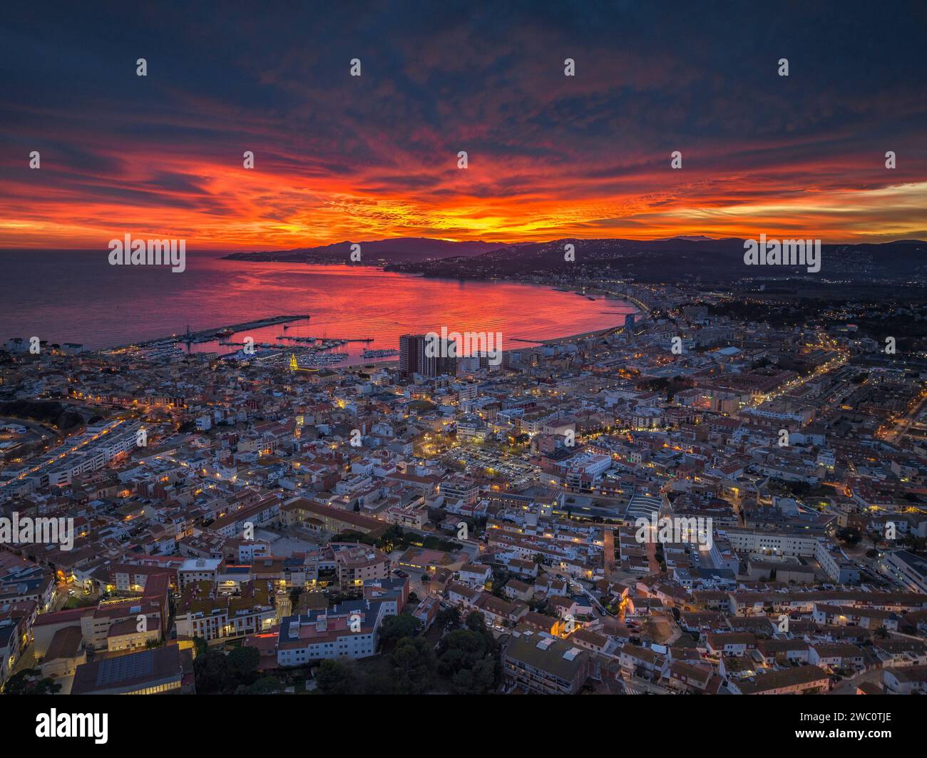 Sunset with a red sky over the bay and city of Palamós. Aerial view (Costa Brava, Baix Empordà, Girona, Catalonia, Spain) Stock Photo