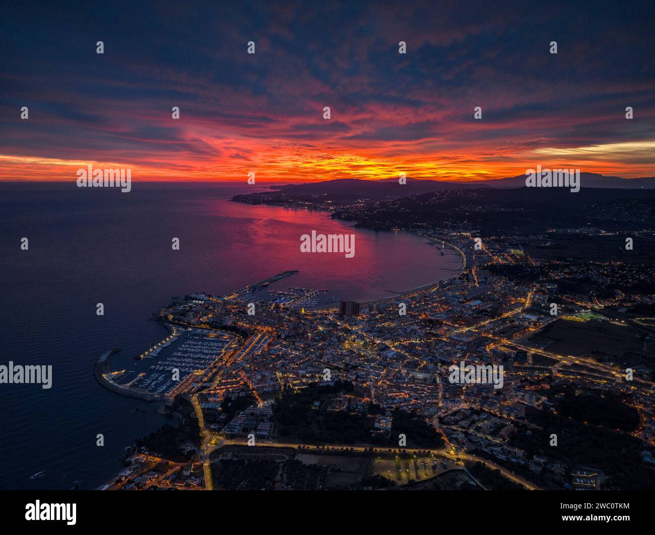 Sunset with a red sky over the bay and city of Palamós. Aerial view (Costa Brava, Baix Empordà, Girona, Catalonia, Spain) Stock Photo