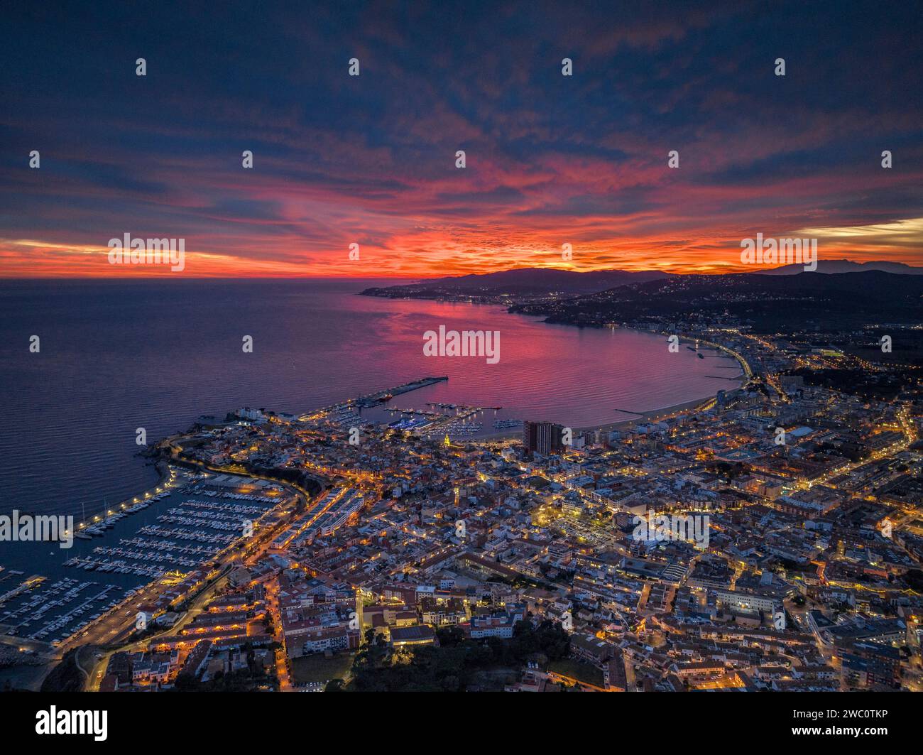 Sunset with a red sky over the bay and city of Palamós. Aerial view (Costa Brava, Baix Empordà, Girona, Catalonia, Spain) Stock Photo