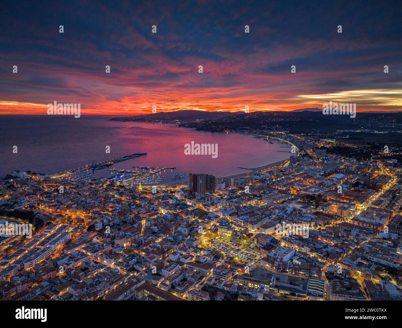 Sunset with a red sky over the bay and city of Palamós. Aerial view (Costa Brava, Baix Empordà, Girona, Catalonia, Spain) Stock Photo