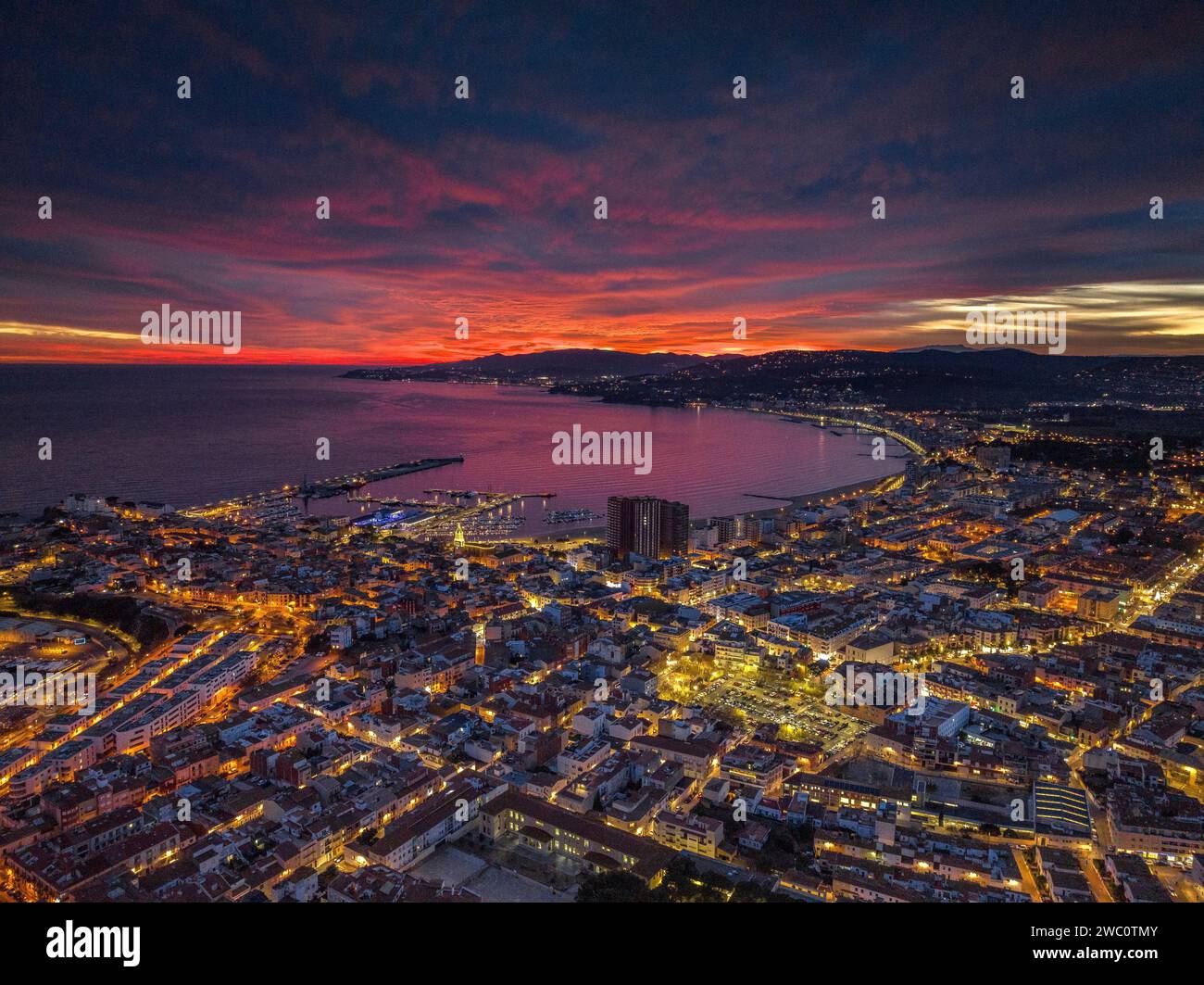 Sunset with a red sky over the bay and city of Palamós. Aerial view (Costa Brava, Baix Empordà, Girona, Catalonia, Spain) Stock Photo