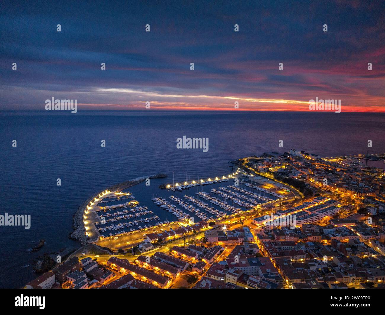 Sunset with a red sky over the bay and city of Palamós. Aerial view (Costa Brava, Baix Empordà, Girona, Catalonia, Spain) Stock Photo