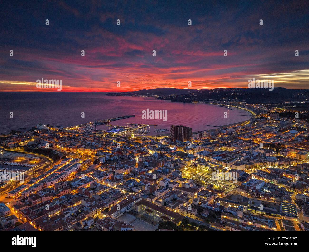 Sunset with a red sky over the bay and city of Palamós. Aerial view (Costa Brava, Baix Empordà, Girona, Catalonia, Spain) Stock Photo