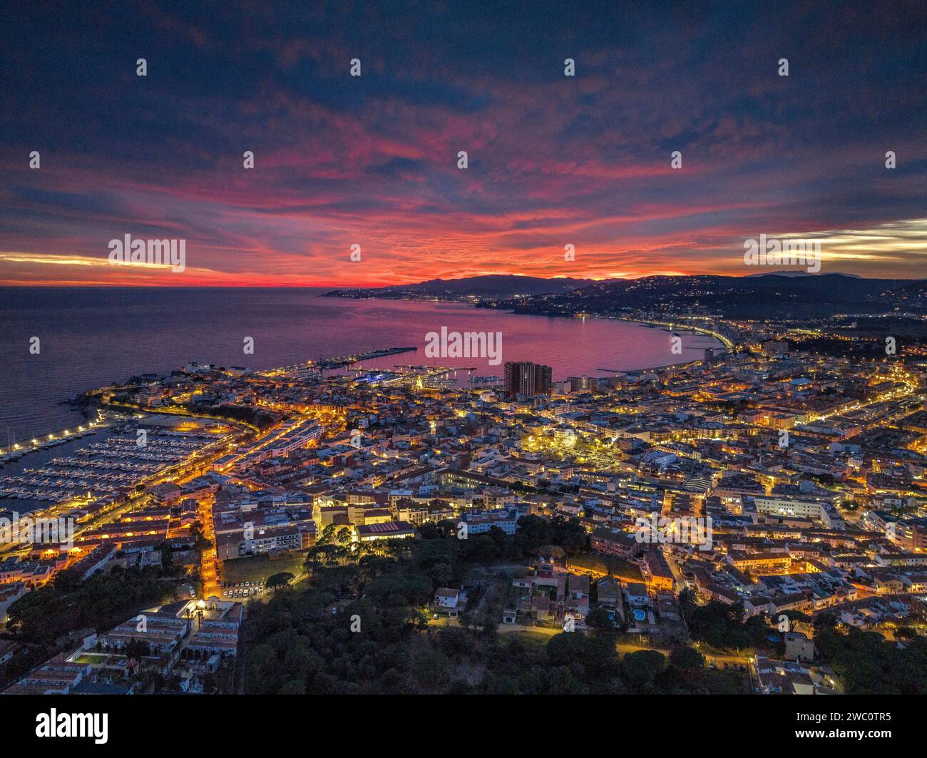Sunset with a red sky over the bay and city of Palamós. Aerial view (Costa Brava, Baix Empordà, Girona, Catalonia, Spain) Stock Photo