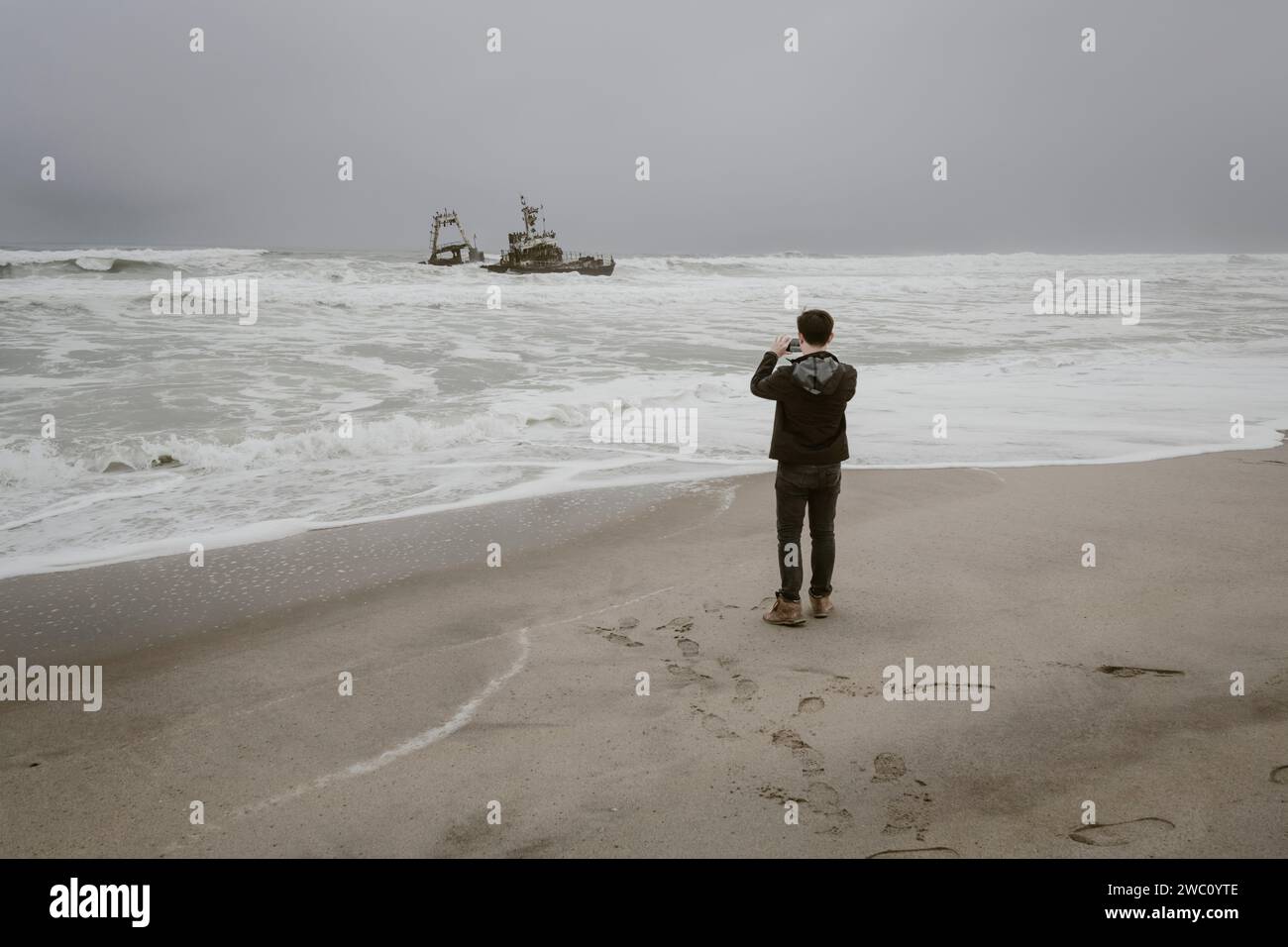 A tourist takes a picture of one of the Shipwrecks on the Skeleton Coast in Namibia Stock Photo