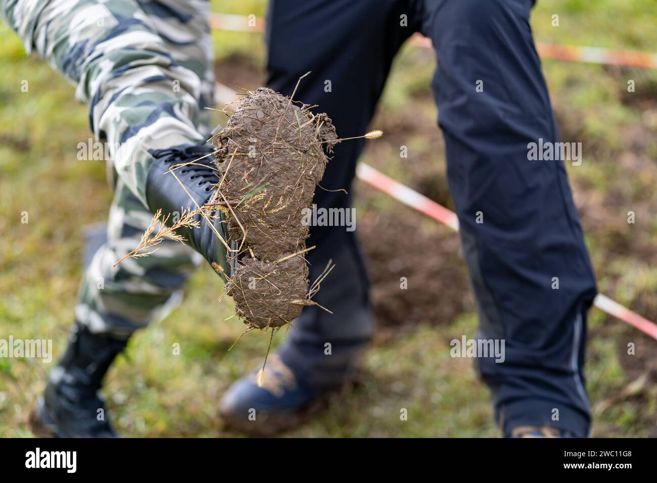 A close-up shot of a person wearing boots covered in mud Stock Photo