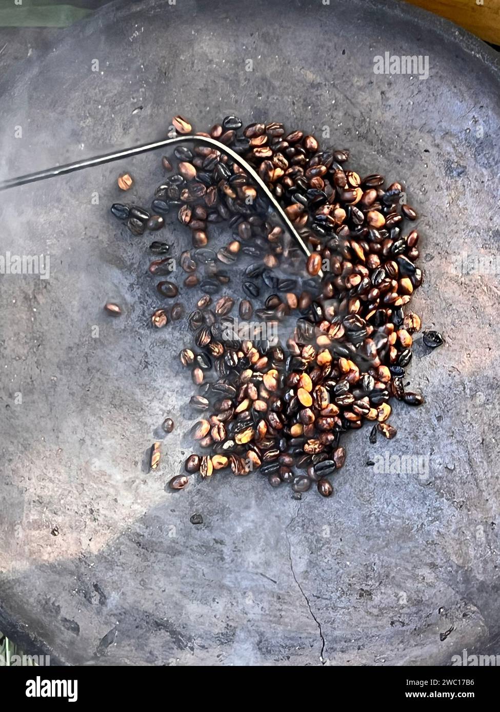 coffee beans being roasted by hand in the traditional way on a wood-fired stove seen from above through the smoke Stock Photo