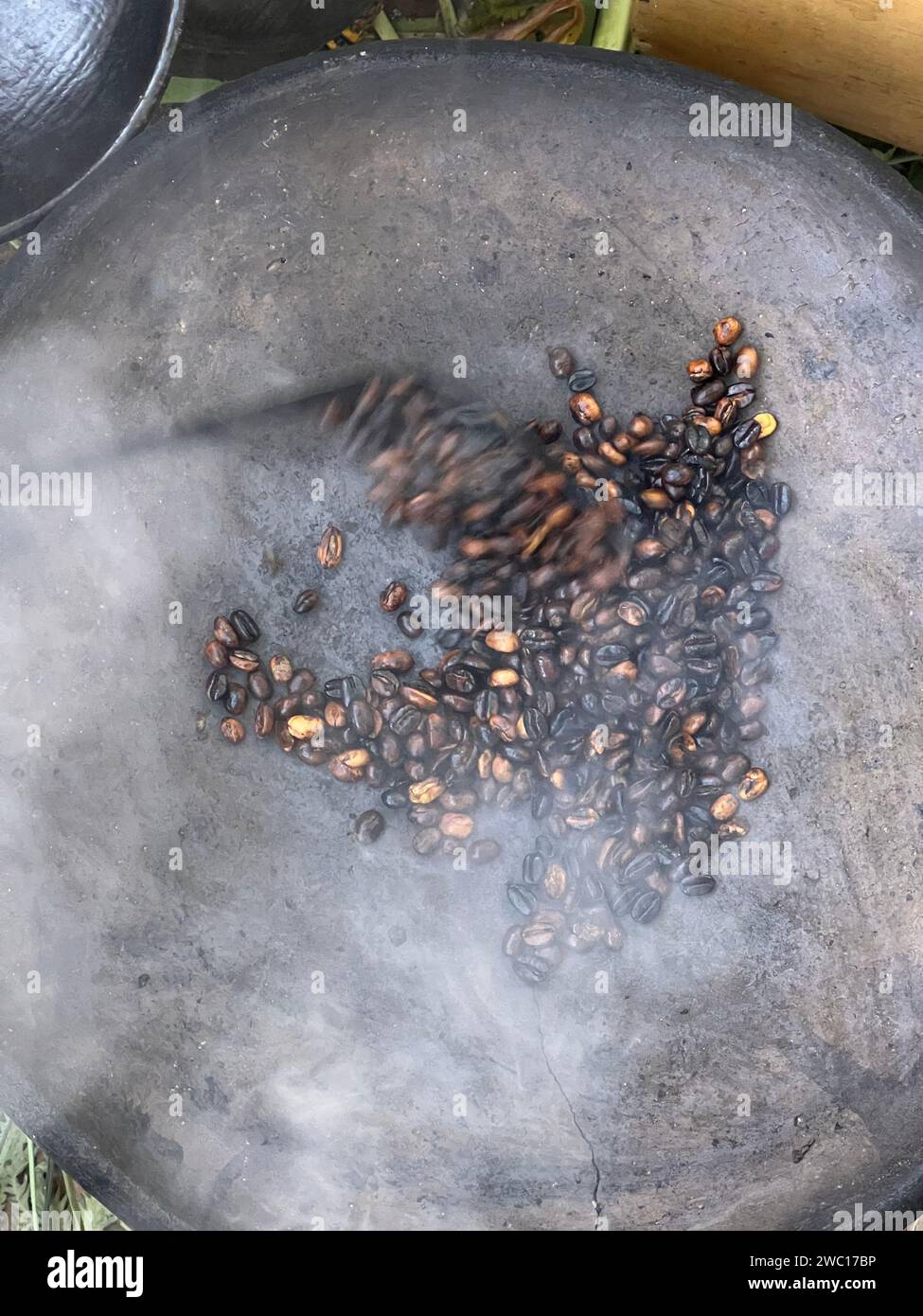 coffee beans being roasted by hand in the traditional way on a wood-fired stove seen from above through the smoke Stock Photo