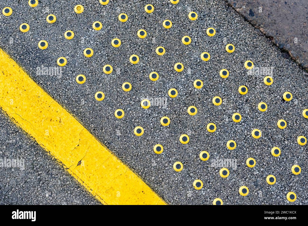 Tactile warning strip, yellow line with black and yellow studs at railway platform edge, United Kingdom Stock Photo