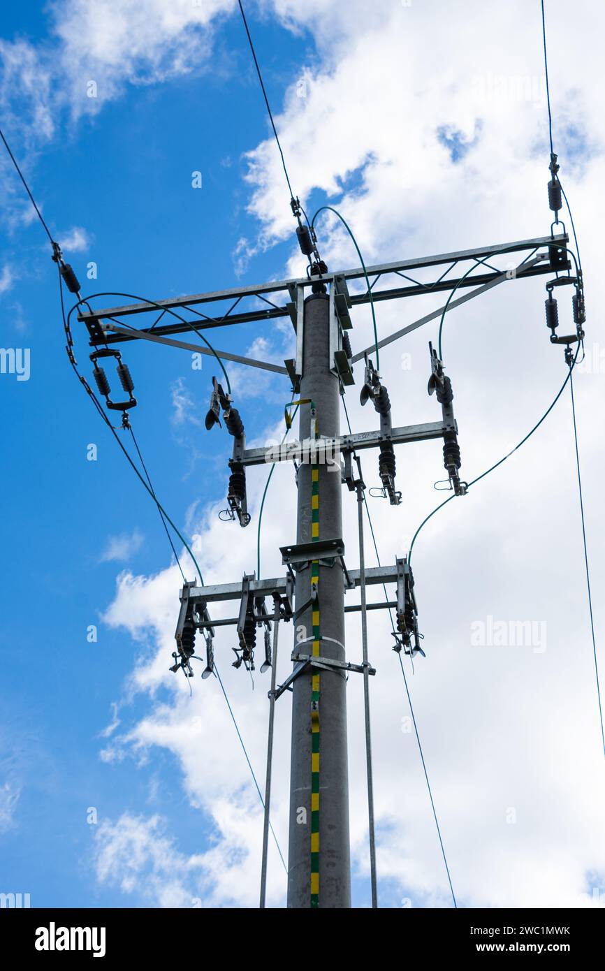 high voltage overhead line, pole with insulators and disconnectors, white clouds in the blue sky Stock Photo
