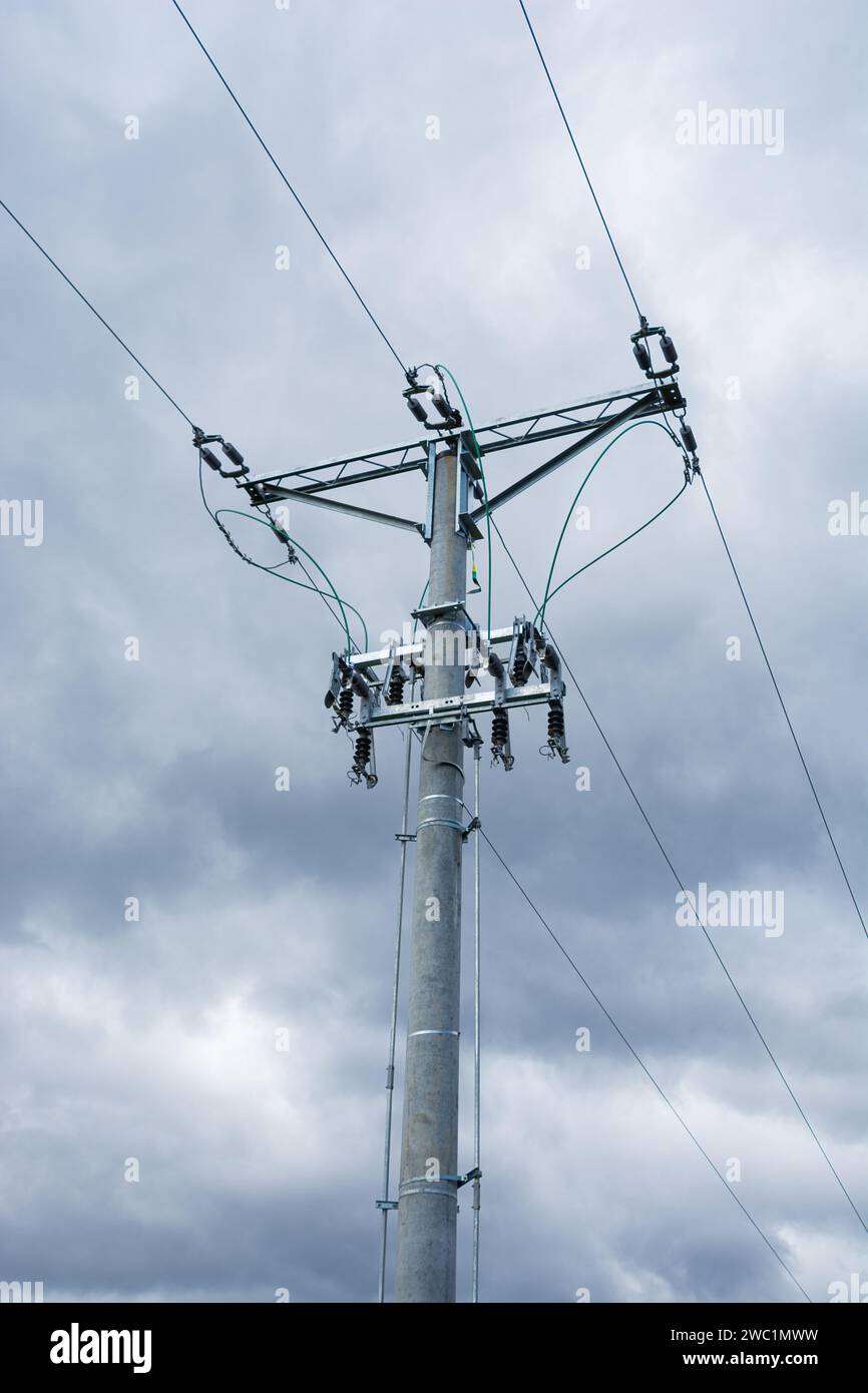 medium voltage overhead line, pole with insulators and disconnectors, dark clouds in the background Stock Photo