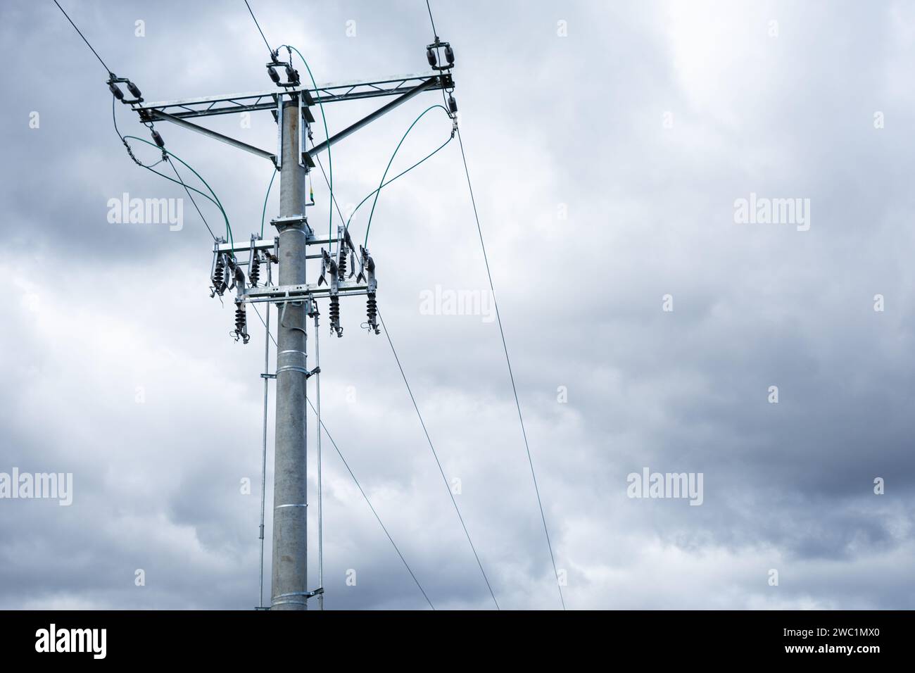 high voltage overhead line, pole with insulators and disconnectors, dark clouds in the background Stock Photo