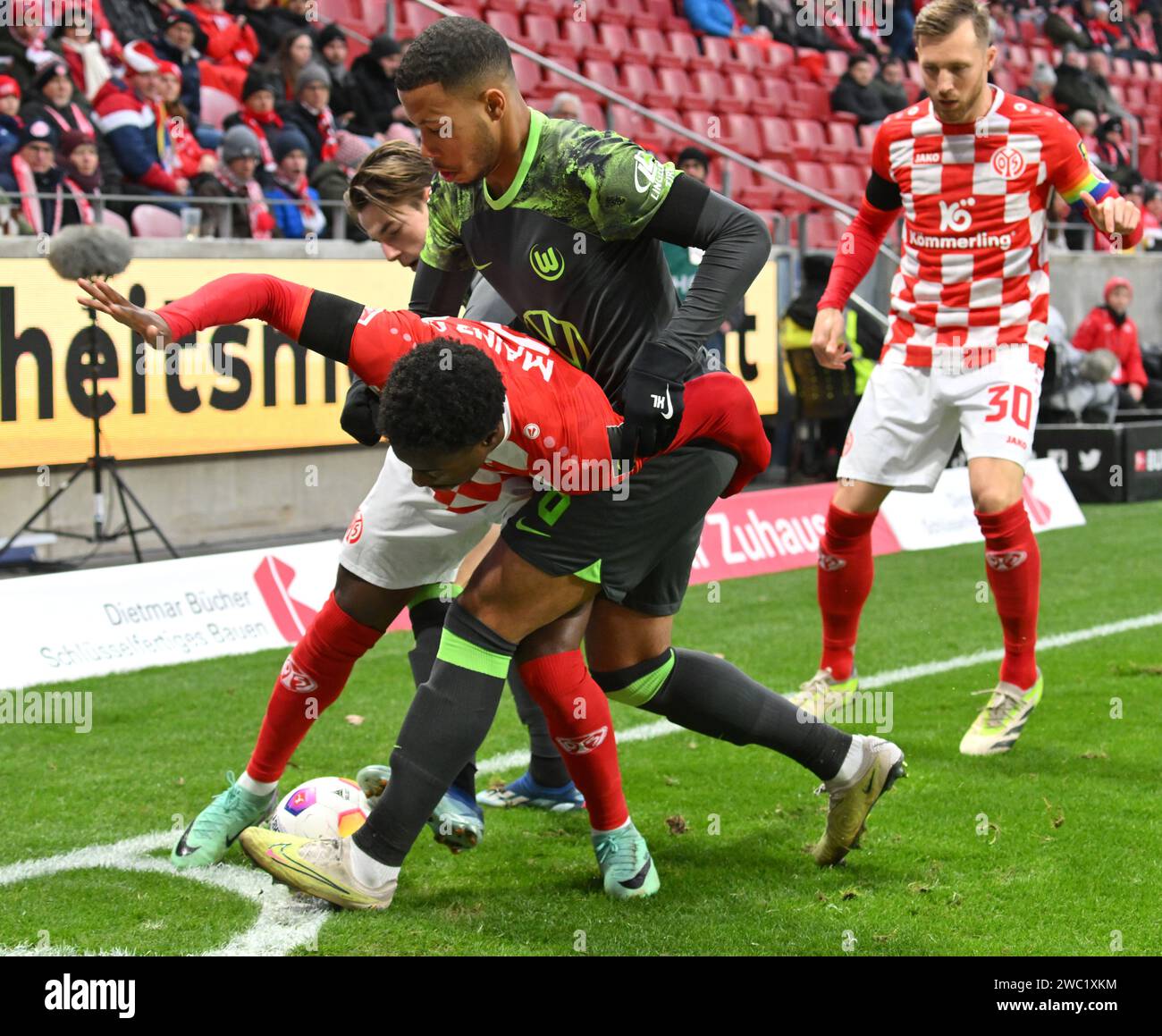 Mainz, Germany. 13th Jan, 2024. Soccer: Bundesliga, FSV Mainz 05 - VfL Wolfsburg, Matchday 17, Mewa Arena: Mainz's Merveille Papela (l) plays against Wolfsburg's Aster Vranckx. Credit: Torsten Silz/dpa - IMPORTANT NOTE: In accordance with the regulations of the DFL German Football League and the DFB German Football Association, it is prohibited to utilize or have utilized photographs taken in the stadium and/or of the match in the form of sequential images and/or video-like photo series./dpa/Alamy Live News Stock Photo