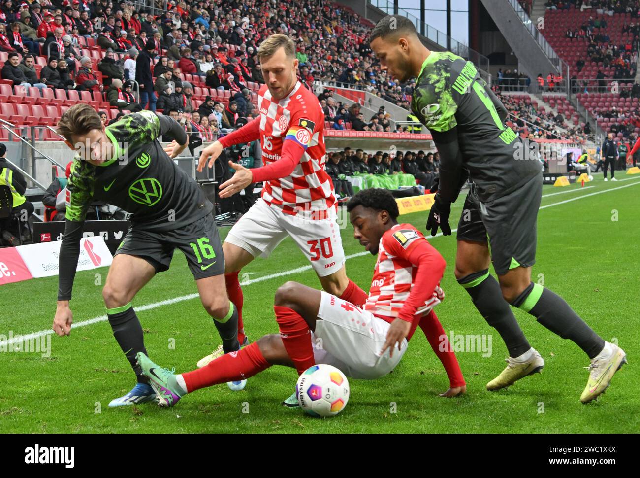 Mainz, Germany. 13th Jan, 2024. Soccer: Bundesliga, FSV Mainz 05 - VfL Wolfsburg, Matchday 17, Mewa Arena: Mainz's Merveille Papela plays against Wolfsburg's Aster Vranckx and Jakub Kaminski (l.) Credit: Torsten Silz/dpa - IMPORTANT NOTE: In accordance with the regulations of the DFL German Football League and the DFB German Football Association, it is prohibited to utilize or have utilized photographs taken in the stadium and/or of the match in the form of sequential images and/or video-like photo series./dpa/Alamy Live News Stock Photo