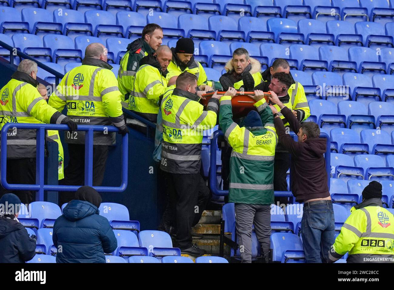 Stewards and Paramedics lift a stretcher down from the stand during a
