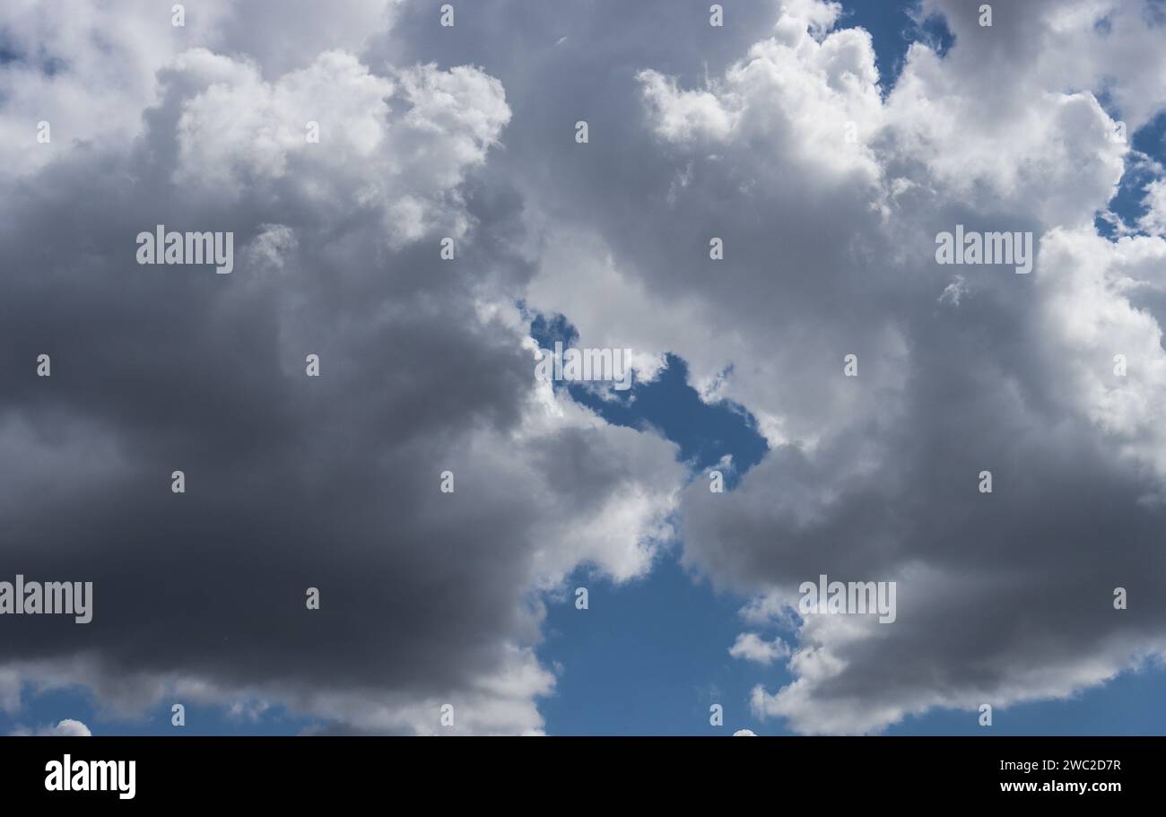 Blue sky with gray cumulus clouds. Solid gray clouds before rain. Stock Photo