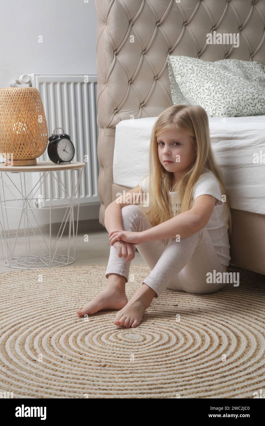 Angry and sad little girl sitting in the bedroom floor Stock Photo - Alamy