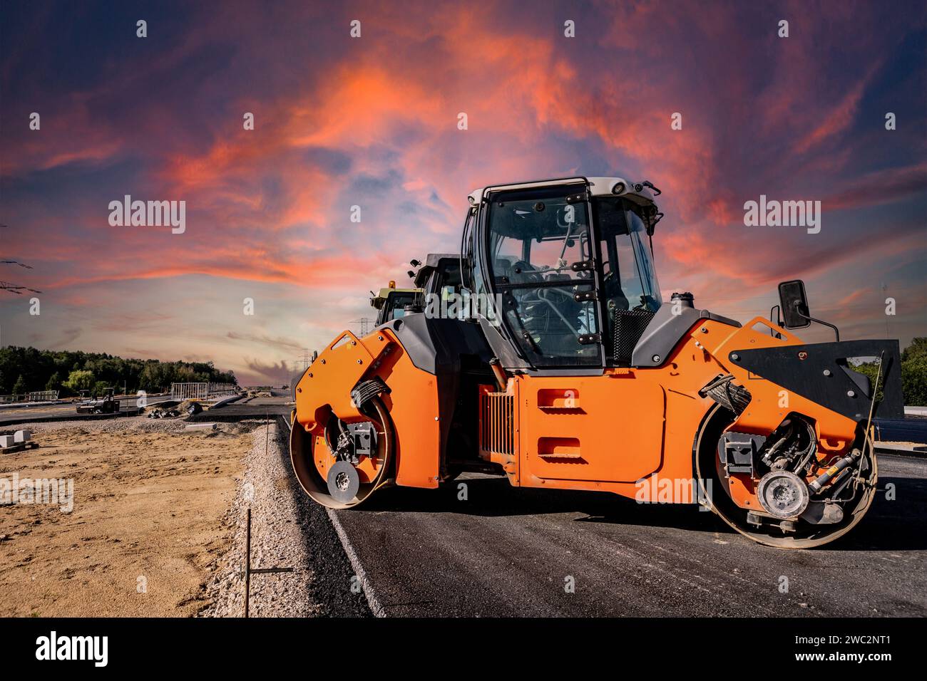 Highway construction. Pouring asphalt, installing sound barriers. Heavy construction equipment on the construction site, roller, excavator, bulldozer Stock Photo