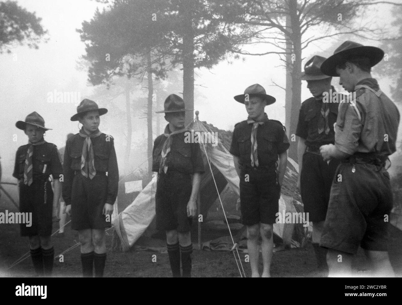 1941, historical, whitsun and an early misty morning at a scout camp at Broadstone, Poole, Dorset, with a curlew troop inspection taking place.  Brownsea Island, also near Poole, was in 1907, the place where the founder of the Scout movement, British Army Officier, Robert Baden-Powell first set up his trial camp for boys and the following year published his famous book, Scouting for Boys. Two years later, with his sister, Agnes, Baden-Powell founded the Girl Guides. Stock Photo