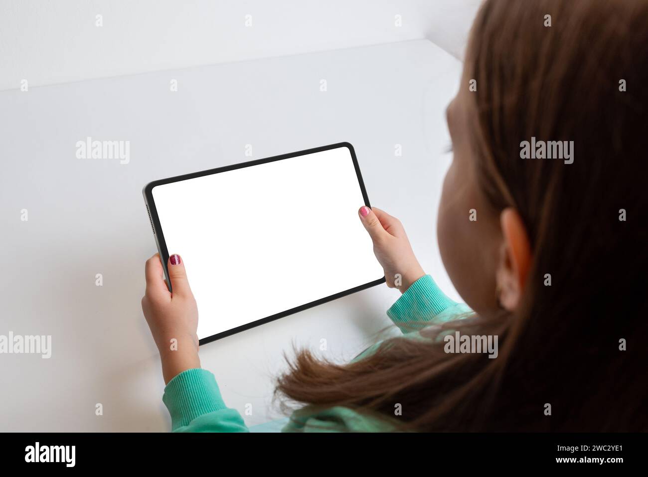 Girl watching a movie on a tablet in a horizontal position at her work desk. Isolated screen for multimedia promotion Stock Photo