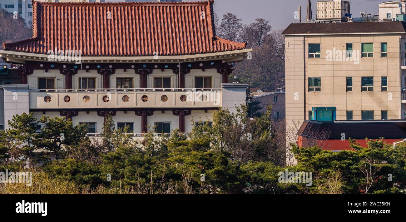 Daejeon, South Korea, March 13, 2017: Building with classical oriental styling with red clay tiled roof, metal mesh windows next to an old, yet Stock Photo