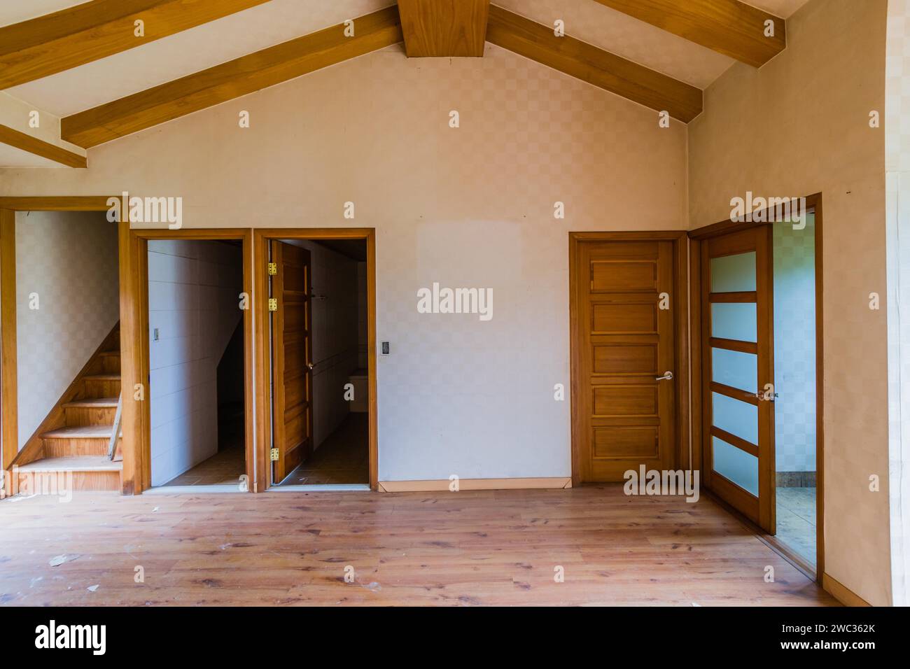 Living room with wood beam ceiling and doors leading to other rooms in two story abandoned house Stock Photo