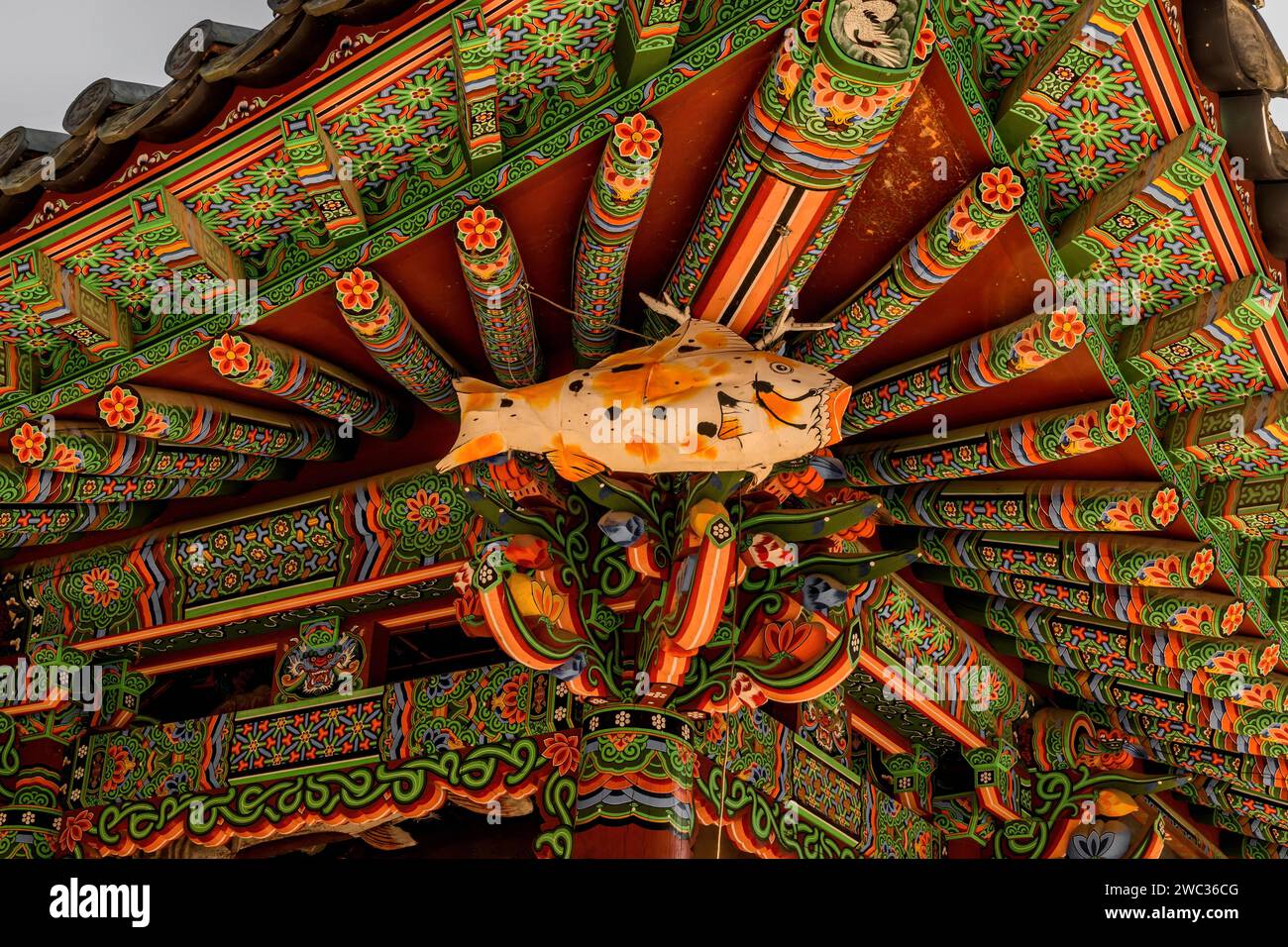 Wooden fish hanging from eves of colorful Buddhist pavilion Stock Photo