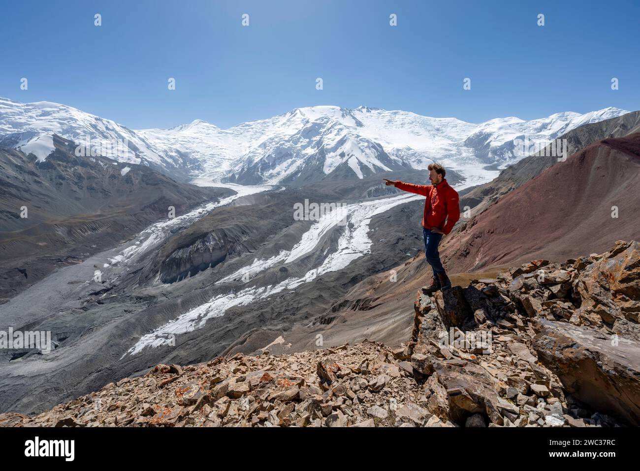 Mountaineer points into the distance, at Traveller's Pass with view of impressive mountain landscape, high mountain landscape with glacier moraines Stock Photo