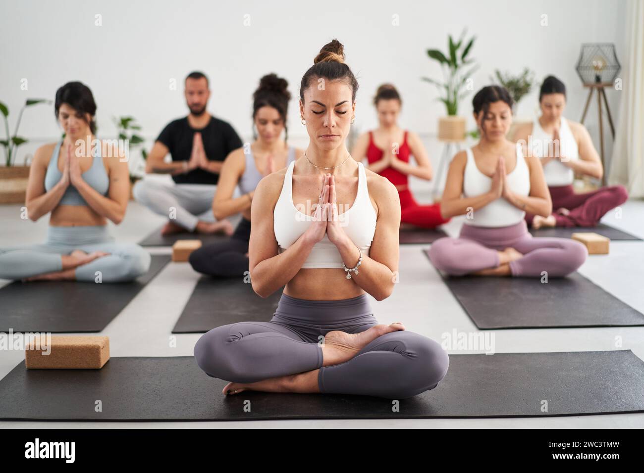 Group diverse fitness people practicing yoga mudra exercises in class, asana posture eyes closed Stock Photo