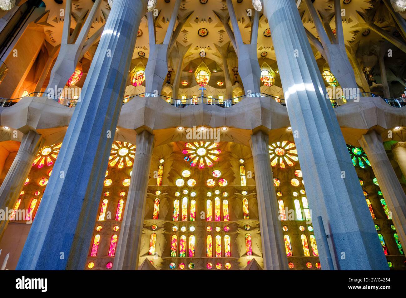 Interior low angle view of light shining through designed stained glass windows inside Basilica La Sagrada Familia, by Antoni Gaudí, Barcelona, Spain Stock Photo