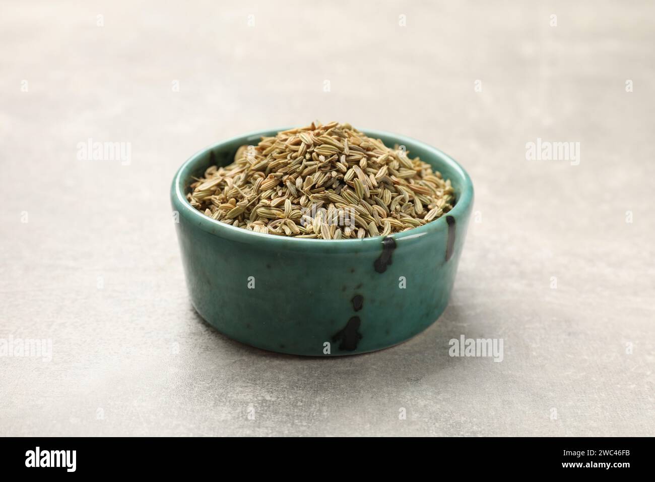 Fennel seeds in bowl on grey table Stock Photo