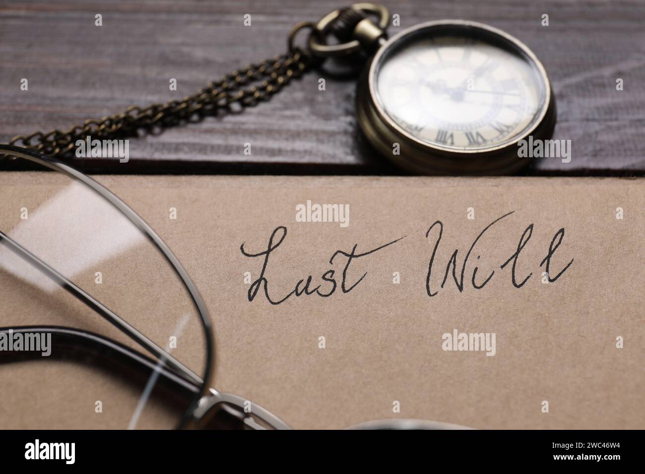 Paper with words Last Will, pocket watch and glasses on wooden table, closeup Stock Photo