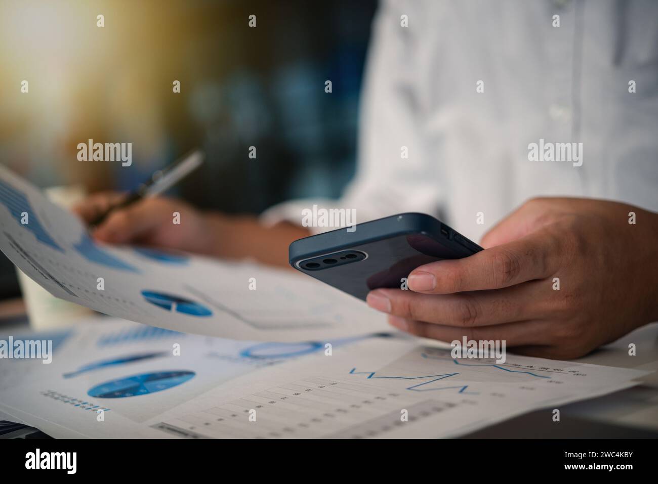 Businessman working with smartphone presentation analyzing data planning documents graphs and chart on desk Stock Photo