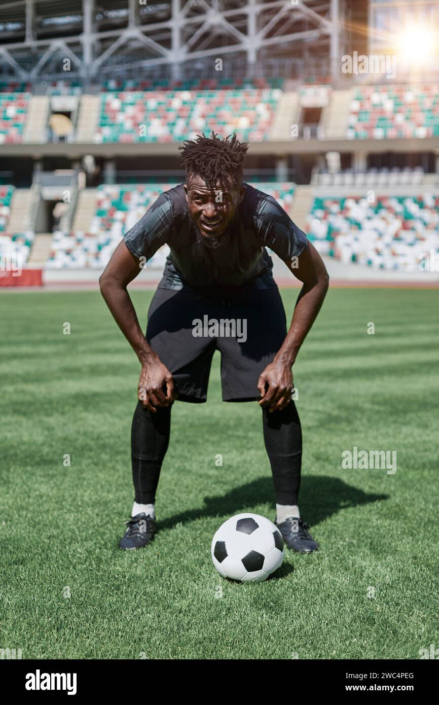 Confident young african american soccer player kicking ball in stadium ...