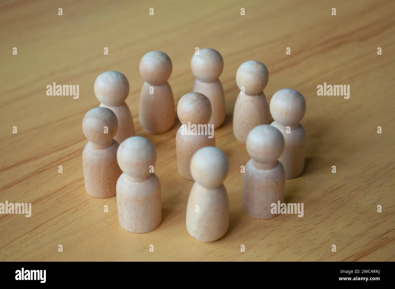 A wooden doll surrounded by other dolls. Representing either leadership or harassment Stock Photo