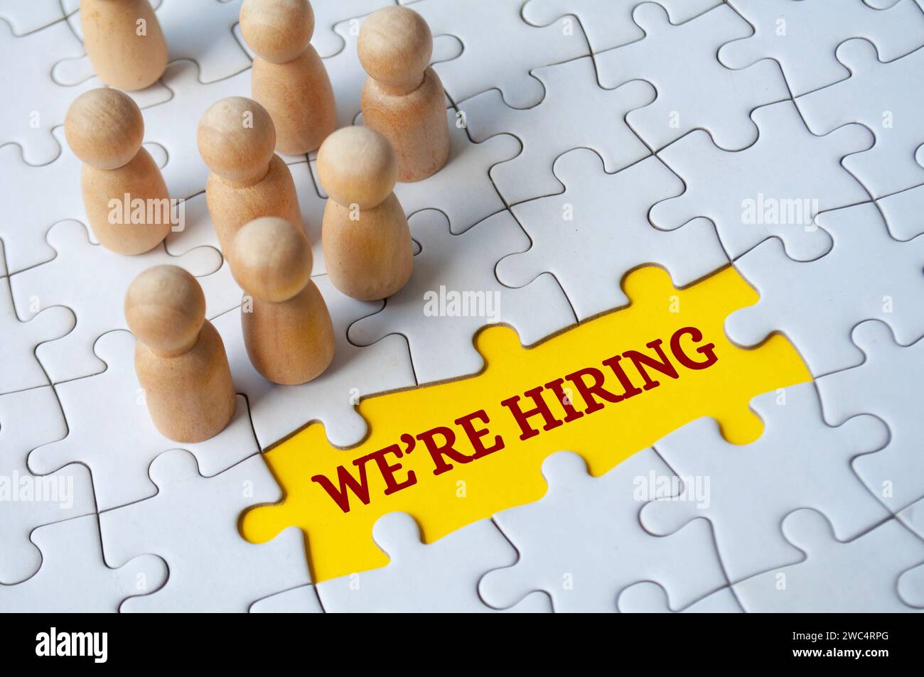We are hiring text on missing jigsaw puzzle with wooden dolls.. Hiring and employment concept