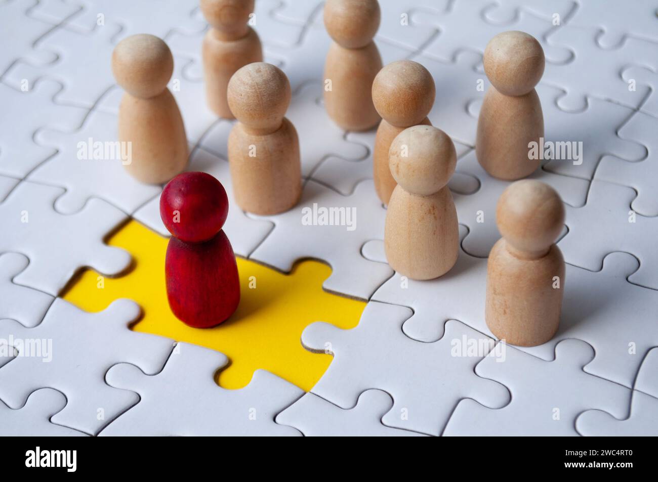Wooden dolls on top of jigsaw with missing jigsaw puzzle. Hiring and employment concept. Stock Photo